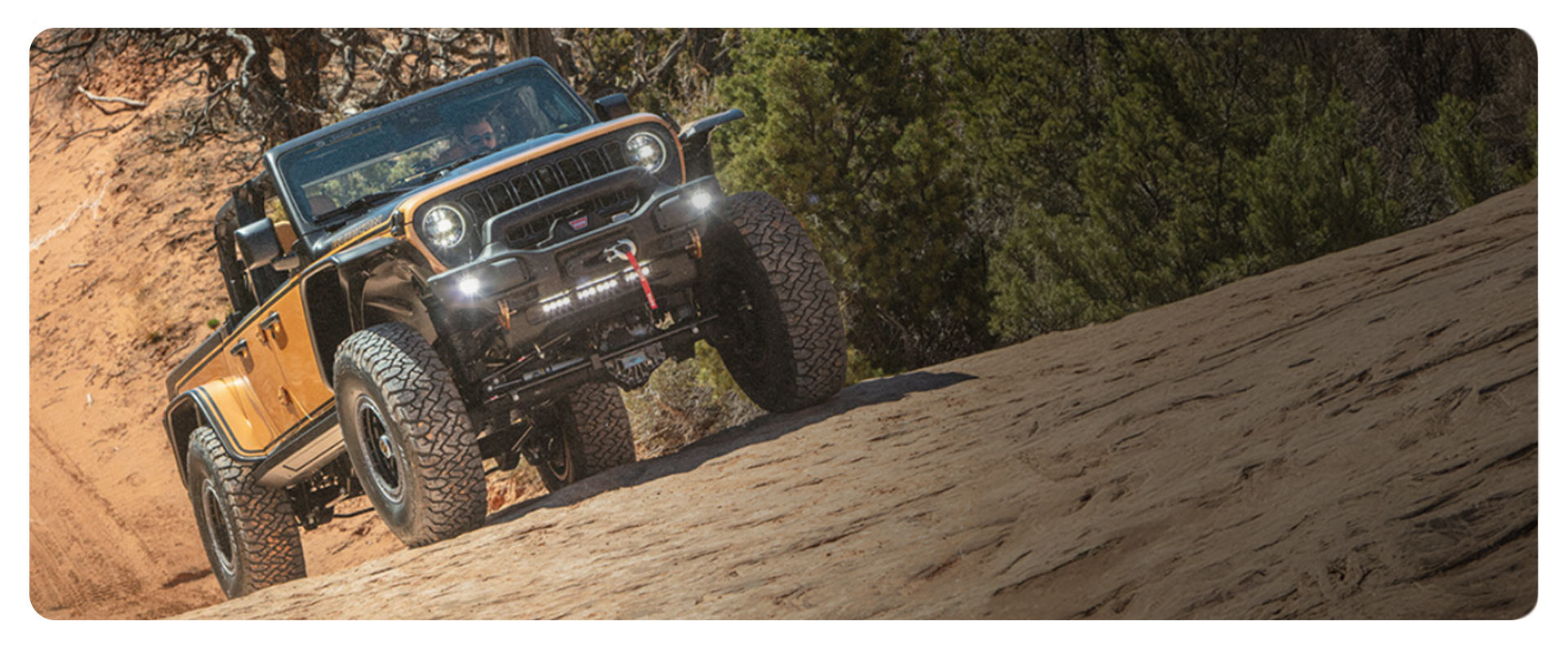 Un vehículo conceptual Jeep Wrangler amarillo descendiendo por una duna pronunciada en el desierto, levantando arena mientras circula.