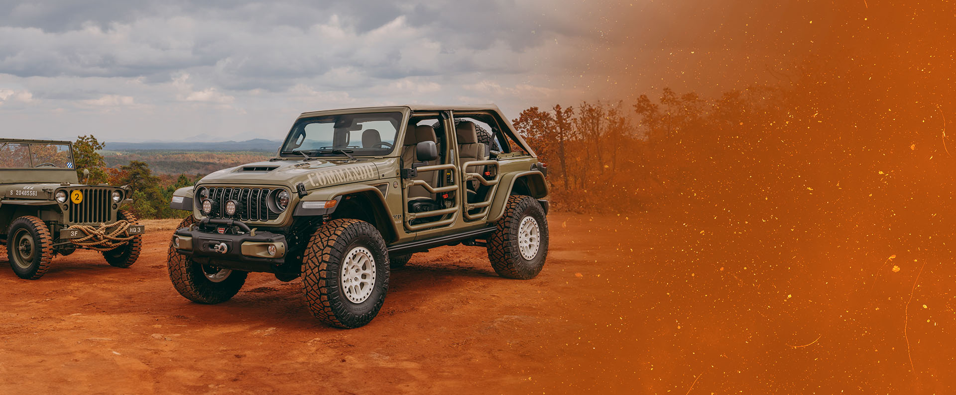A vintage military jeep on the left and an olive drab 2026 Jeep Wrangler Commando with tube doors on the right, both parked on a clearing in the mountains. Fox Factory Vehicles.