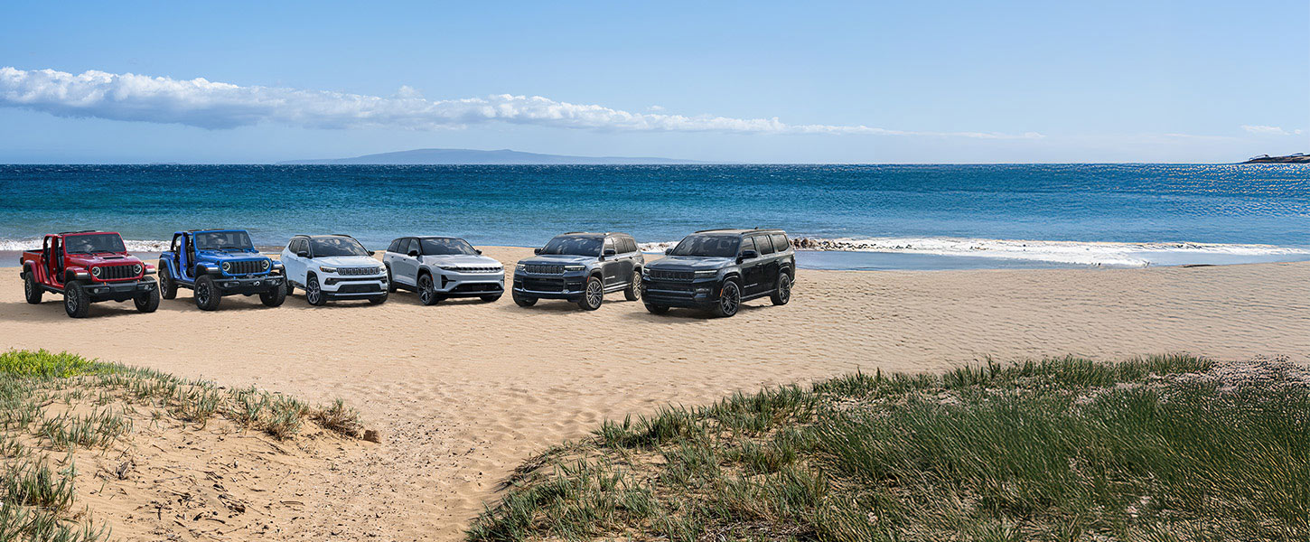 Una fila de seis vehículos de la marca Jeep estacionados en semicírculo, en un claro cubierto de nieve en las montañas. De izquierda a derecha: una Jeep Gladiator Mojave X 2025 roja, un Jeep Wrangler Rubicon X 2025 azul, un Jeep Compass Limited blanco, un Wagoneer S 2025 gris, un Grand Cherokee Summit Reserve 2025 negro y un Jeep Wagoneer Obsidian 2025 negro.