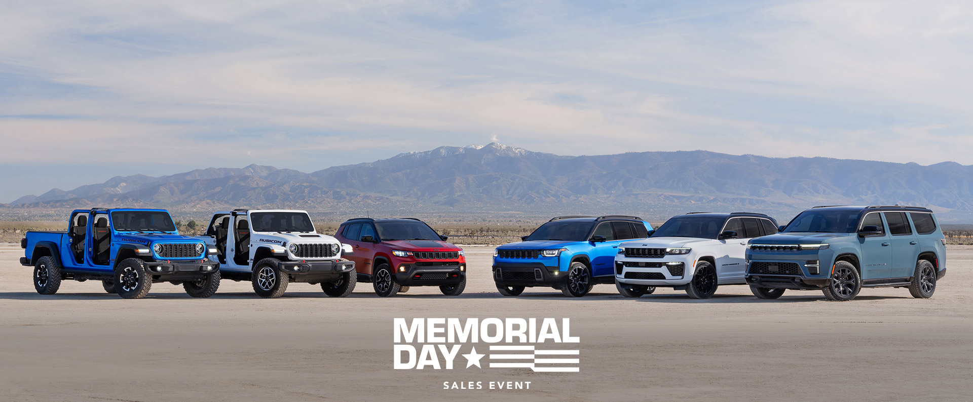 Una línea de seis vehículos Jeep 2026 estacionados en semicírculo. De izquierda a derecha: un Gladiator Rubicon azul y un Wrangler Rubicon X blanco, ambos sin puertas ni techo, un Compass Trailhawk rojo con inserción negra en el capó, un Cherokee Overland azul, un Grand Cherokee Summit Obsidian blanco y un Grand Wagoneer Upland gris azulada. Evento de ventas por el Día de los Caídos.